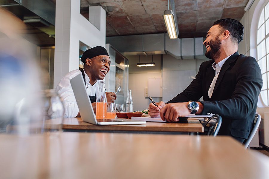 Business Insurance - View of Cheerful Restaurant Manager and Chef Sitting at a Table Having Fun Talking Together