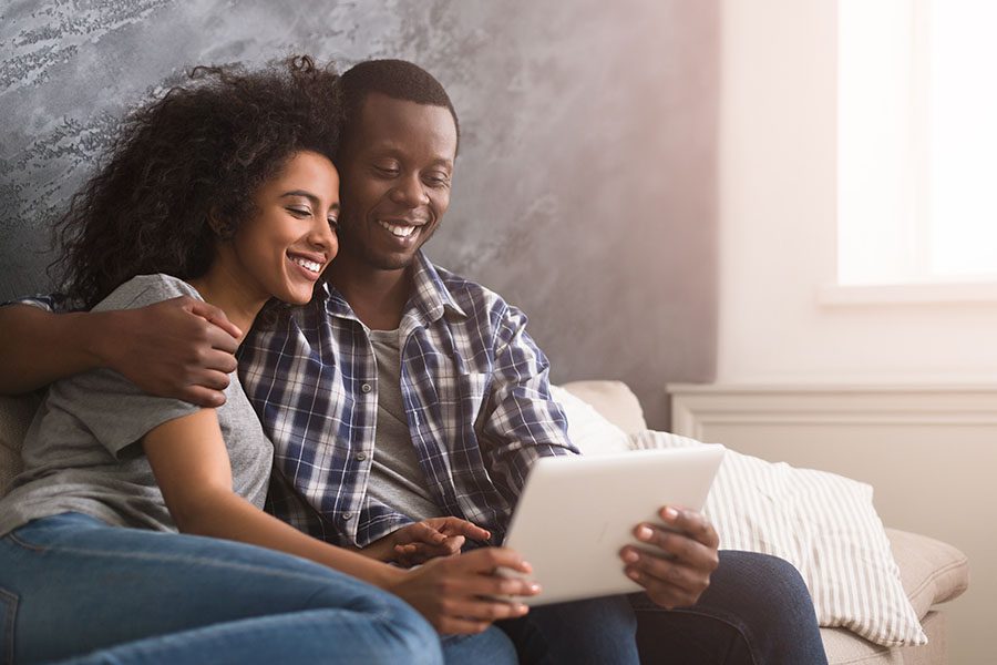 Digital Magazine - Portrait of a Loving Young Couple Sitting on the Sofa While Using a Tablet Together